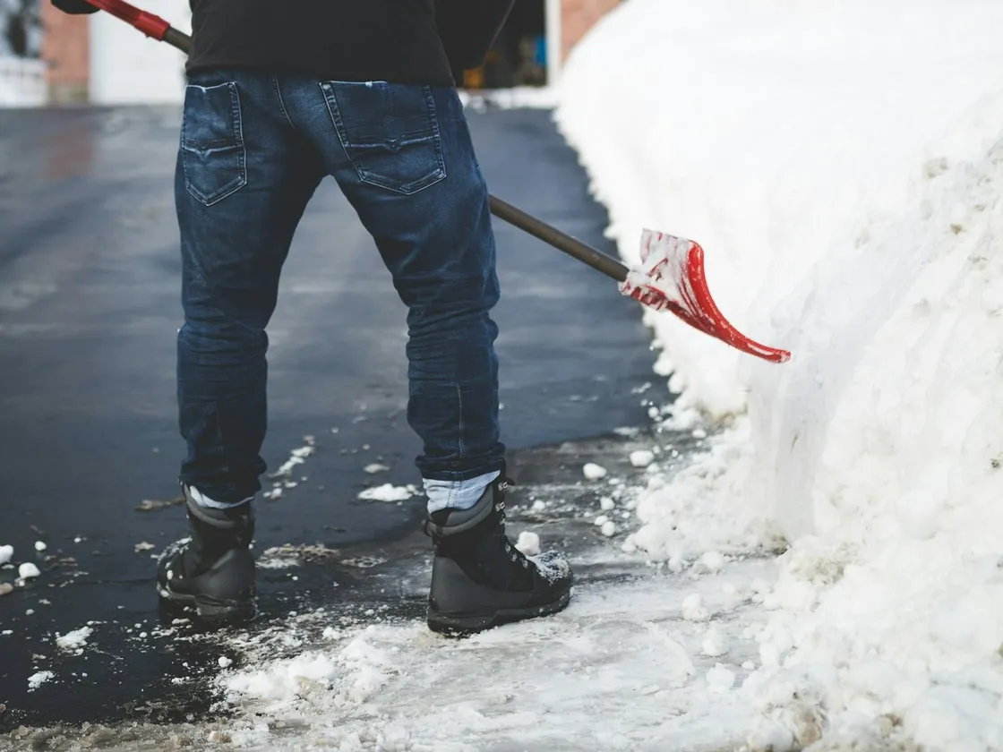 Winterdienst: Eine Zufahrt wird mit der Schneeschaufel vom Schnee befreit